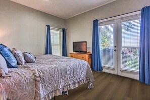 A bedroom with a bed, a television on a wooden stand, and a sliding glass door leading to an outdoor area. - Bonita Circle 206a (Panama City Beach)