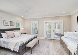 A bedroom with a large bed, a bench, a nightstand, and a ceiling fan. - Crisp Ocean Breeze (Santa Rosa Beach)