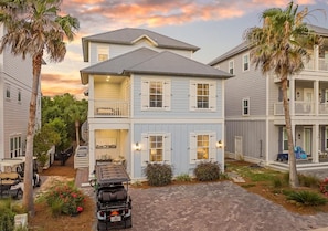 A two-story residential building with a covered porch, a garage, and a driveway. - Crisp Ocean Breeze (Santa Rosa Beach)