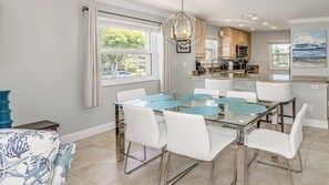 A dining area with a glass table, white chairs, and blue placemats. - Coastal Paradise condo close to public beach (Marco island)