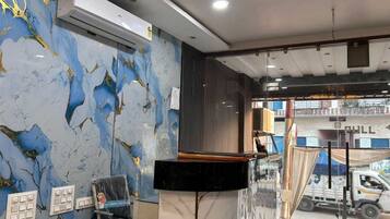 A hotel reception area with marble walls, a reception desk, and a view of the street outside.
