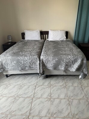 Un lit double avec une couvre-lit à motifs, une table de chevet avec une lampe et une petite table de nuit avec un téléphone.