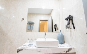 Une salle de bain avec un lavabo en marbre, un miroir, un sèche-cheveux et un porte-serviettes.