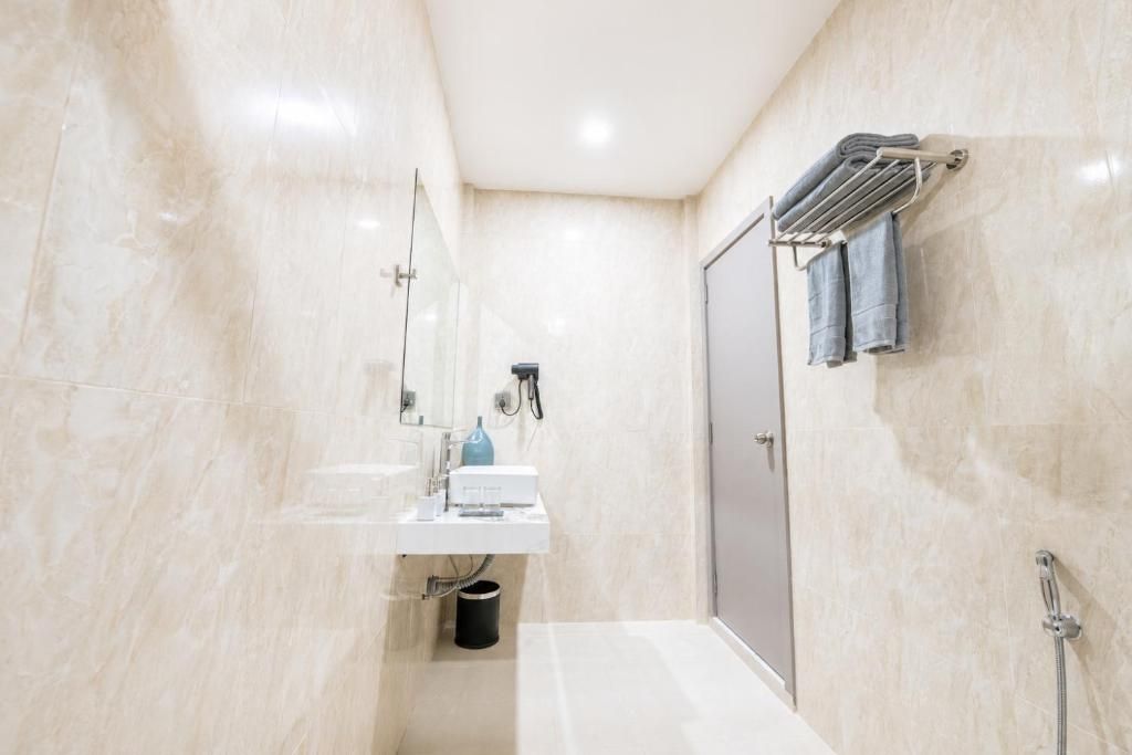A modern bathroom with a glass shower enclosure, a white sink, and a towel rack.