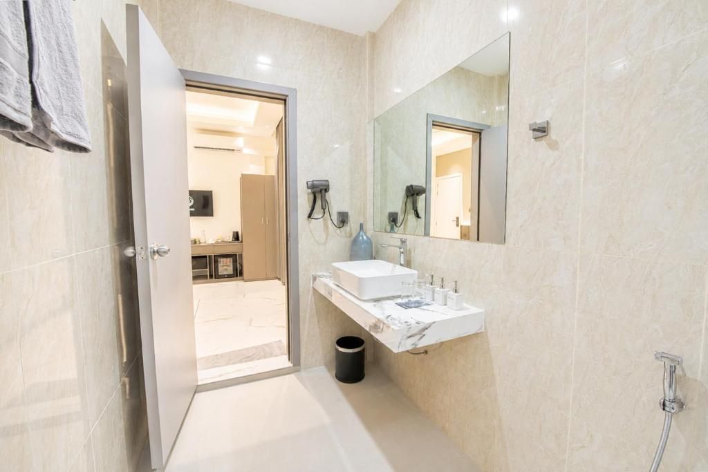 A modern bathroom with a white marble sink, a large mirror, and a shower.
