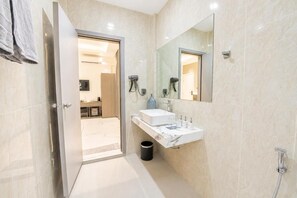 Un baño moderno con lavamanos de mármol blanco, un espejo grande y una ducha.