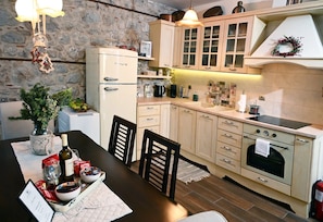 Une cuisine avec un mur en pierre, des placards en bois, un réfrigérateur, un évier et une table à manger avec des chaises.