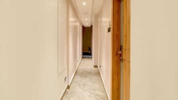 Um corredor com piso de mármore, moldura de porta de madeira e um interruptor na parede.