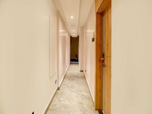 Ein Korridor mit Marmorboden, Holzrahmen an der Tür und einem Lichtschalter an der Wand.