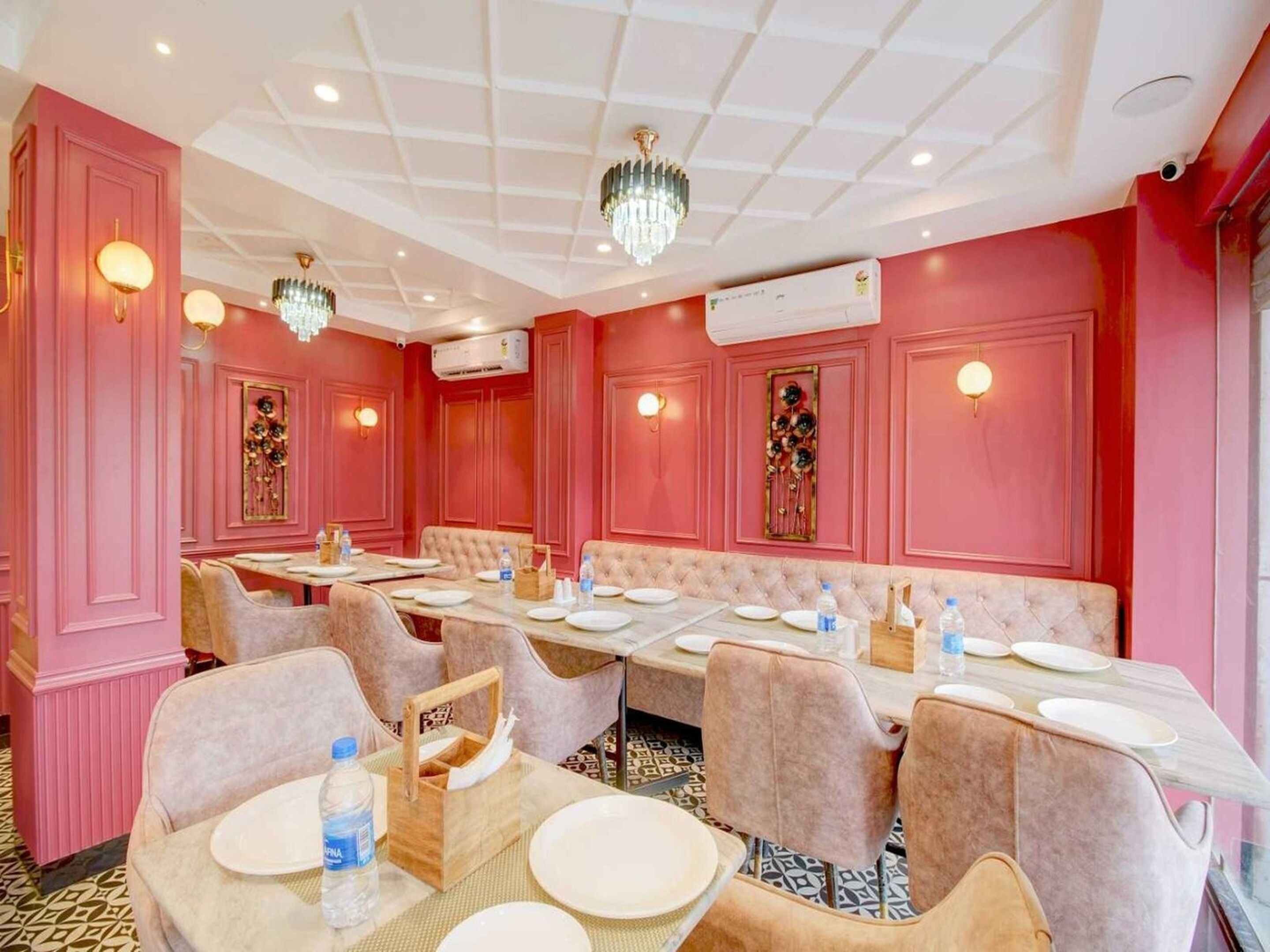 Un comedor con paredes rosadas, candelabros y una disposición central de asientos.