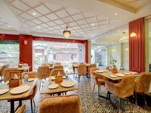 Ein Restaurant mit einer gitterförmigen Decke, Tischen mit Stühlen und Blick nach draußen.