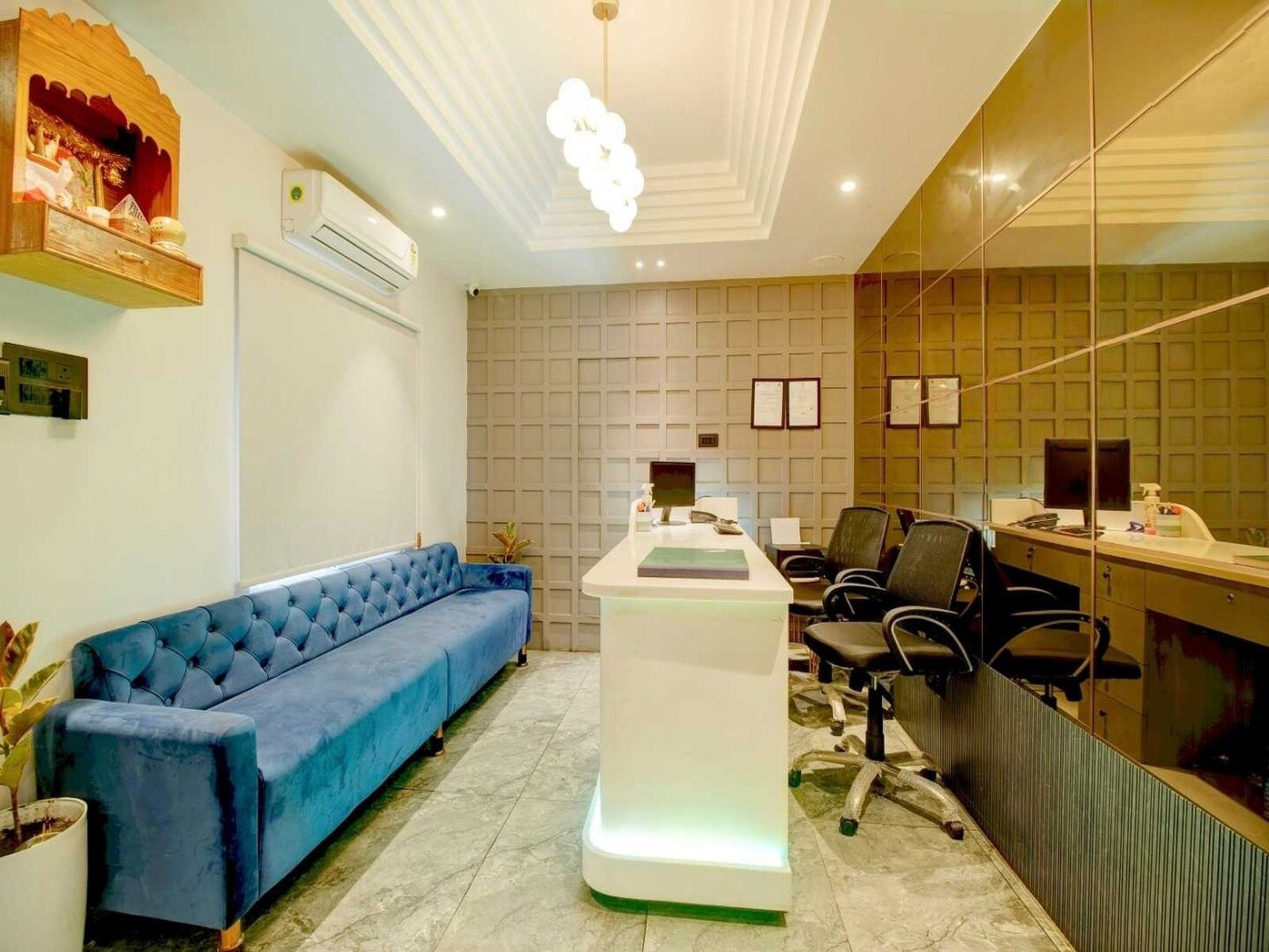A modern office with a blue sofa, a reception desk, and a large mirror.