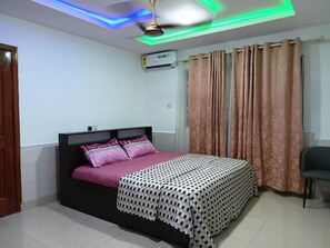 A bedroom with a bed, curtains, a ceiling fan, and an air conditioning unit. - Cozy 1-bedroom apartment in charming Spintex with AC (Spintex)