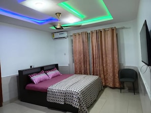 A bedroom with a bed, curtains, a chair, and a ceiling fan. - Cozy 1-bedroom apartment in adorable Spintex with AC (Spintex)