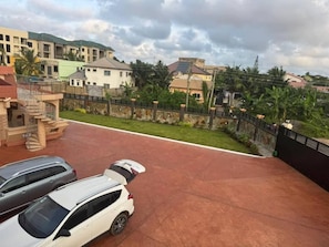 A residential area with a paved driveway, parked cars, and a view of neighboring houses. - Cozy 1-bedroom apartment in adorable Spintex with AC (Spintex)