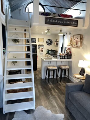 A modern kitchen with a central island, bar stools, and a decorative clock. - Fun & Magical Treehouse (Coweta)