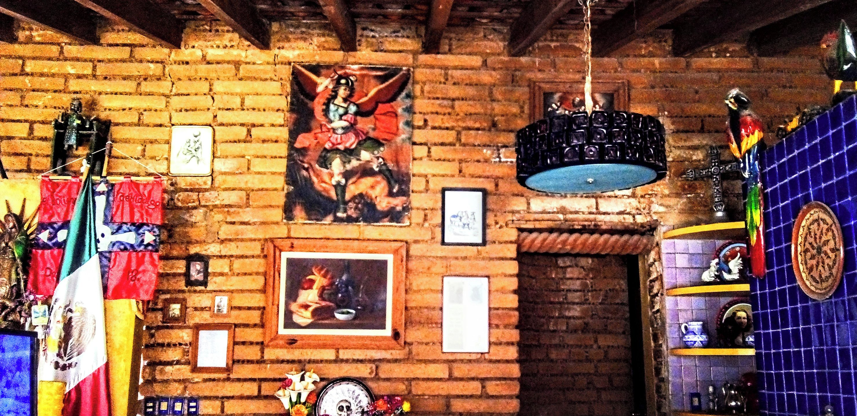 A room with a brick wall, a framed painting, and various decorations including flags and a hanging light fixture.