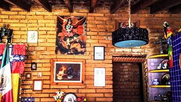 A room with a brick wall, a framed painting, and various decorations including flags and a hanging light fixture.