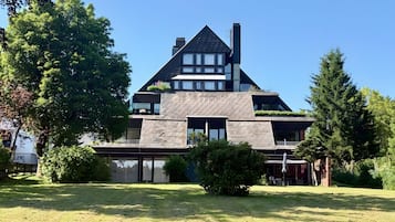 A modern two-story house with a sloped roof, large windows, and a well-maintained lawn.
