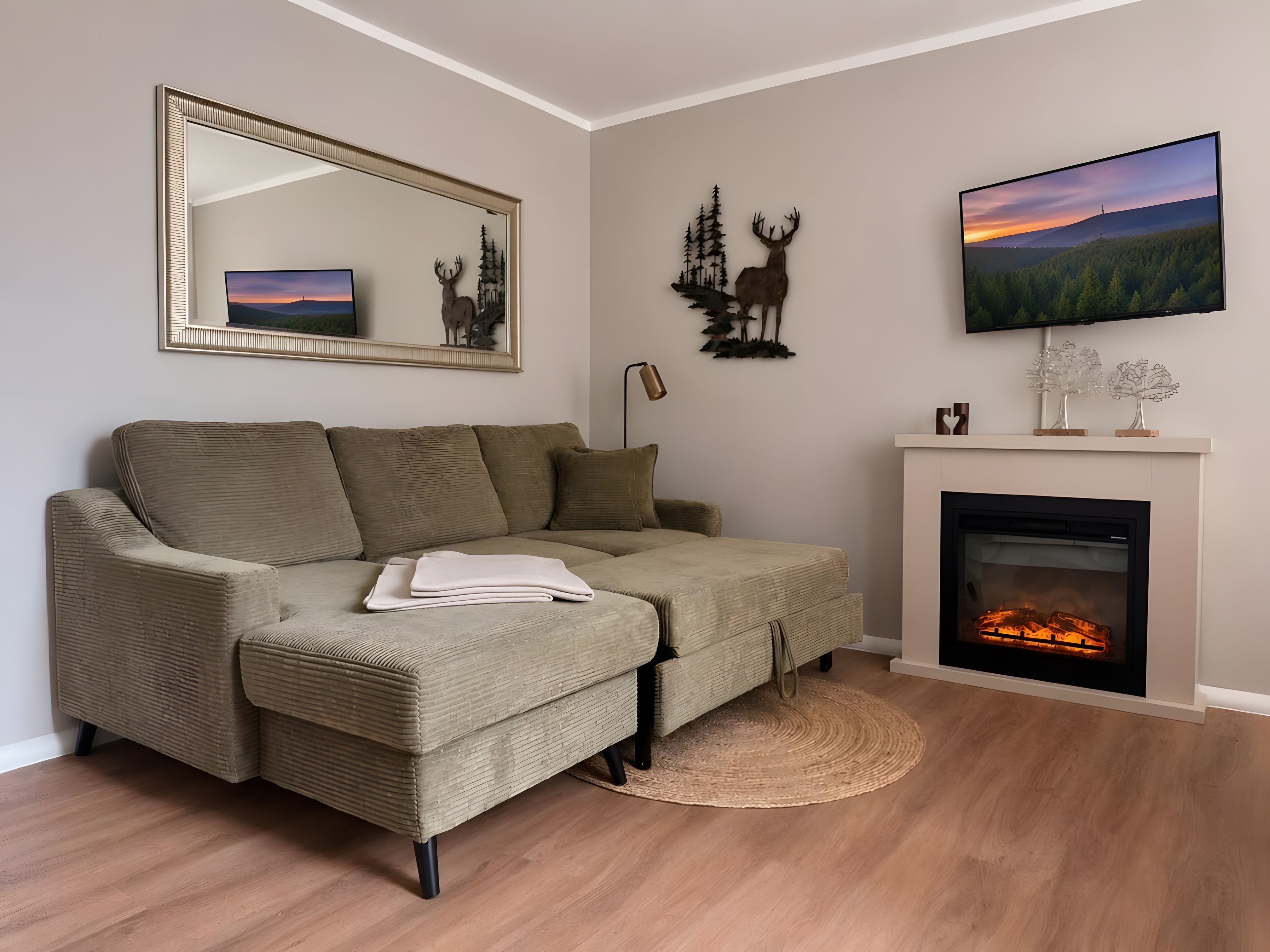 A living room with a sofa, a fireplace, a television, and wall art.