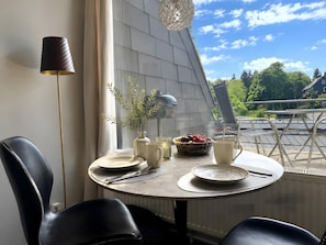 Ett matbord med tallrikar, bestick, en vas med gröna växter och en korg med frukt.