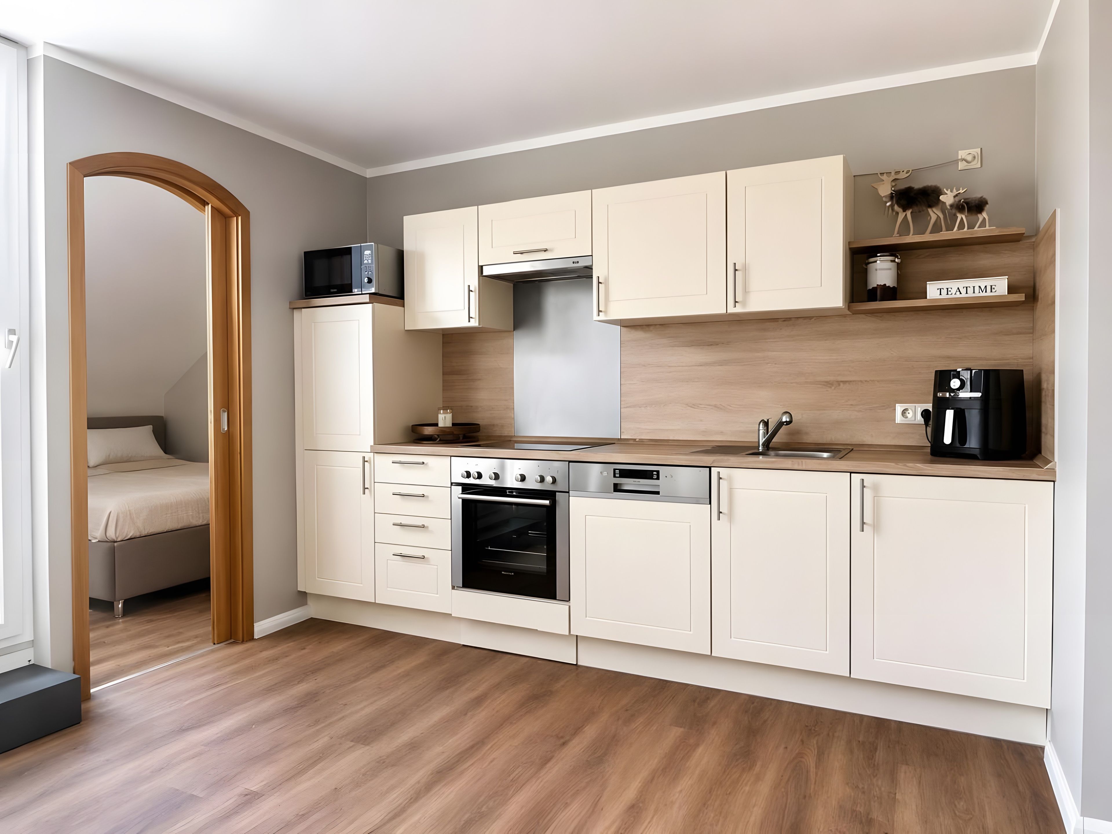 A modern kitchen with white cabinets, a built-in oven, and a coffee machine.