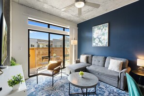 A modern living room with a grey sofa, a round coffee table, and a blue patterned rug. - Lovely 2BR | Pool + W/D | Near Arts District (Phoenix)