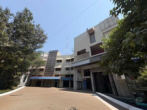 A multi-story building with a flat facade, a visible entrance, and a clear sky. - Deluxe Hotel Saubhagyashanti (Nashik)