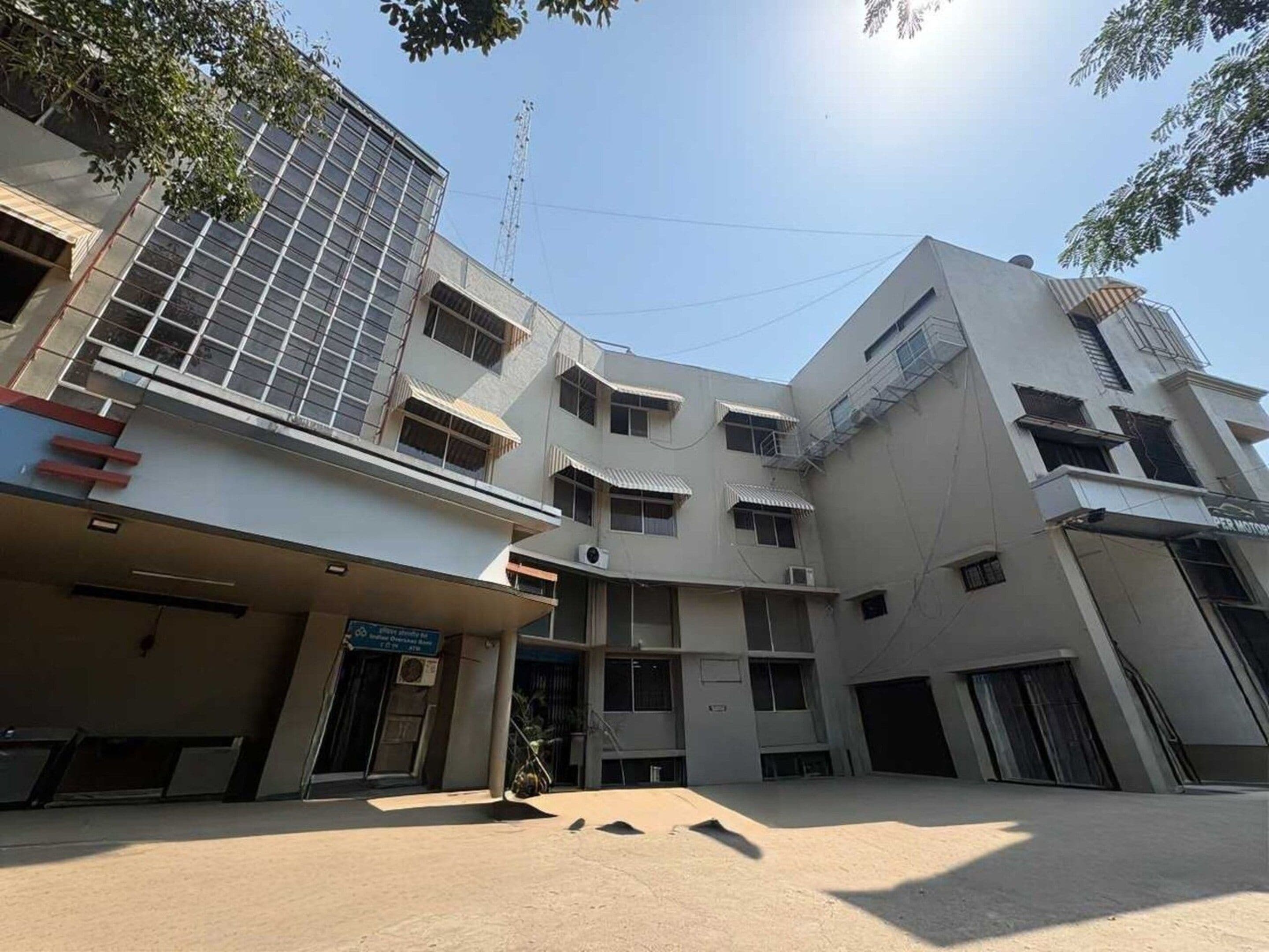A multi-story building with a flat facade, multiple windows, and a covered entrance area.