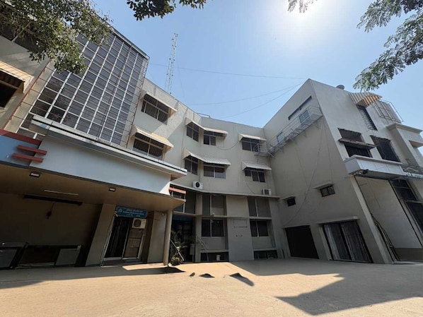 A multi-story building with a flat facade, multiple windows, and a covered entrance area.