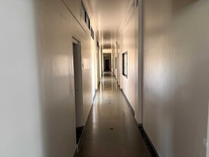A long, narrow hallway with doors on both sides and a light-colored floor.