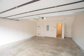 A spacious, empty room with a concrete floor, white walls, and a door leading to another room. - Great Location Near Gulch, 12 South & Broadway (Nashville)