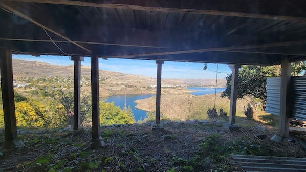 Ett takförsett utomhusområde med utsikt över en sjö och kullar.