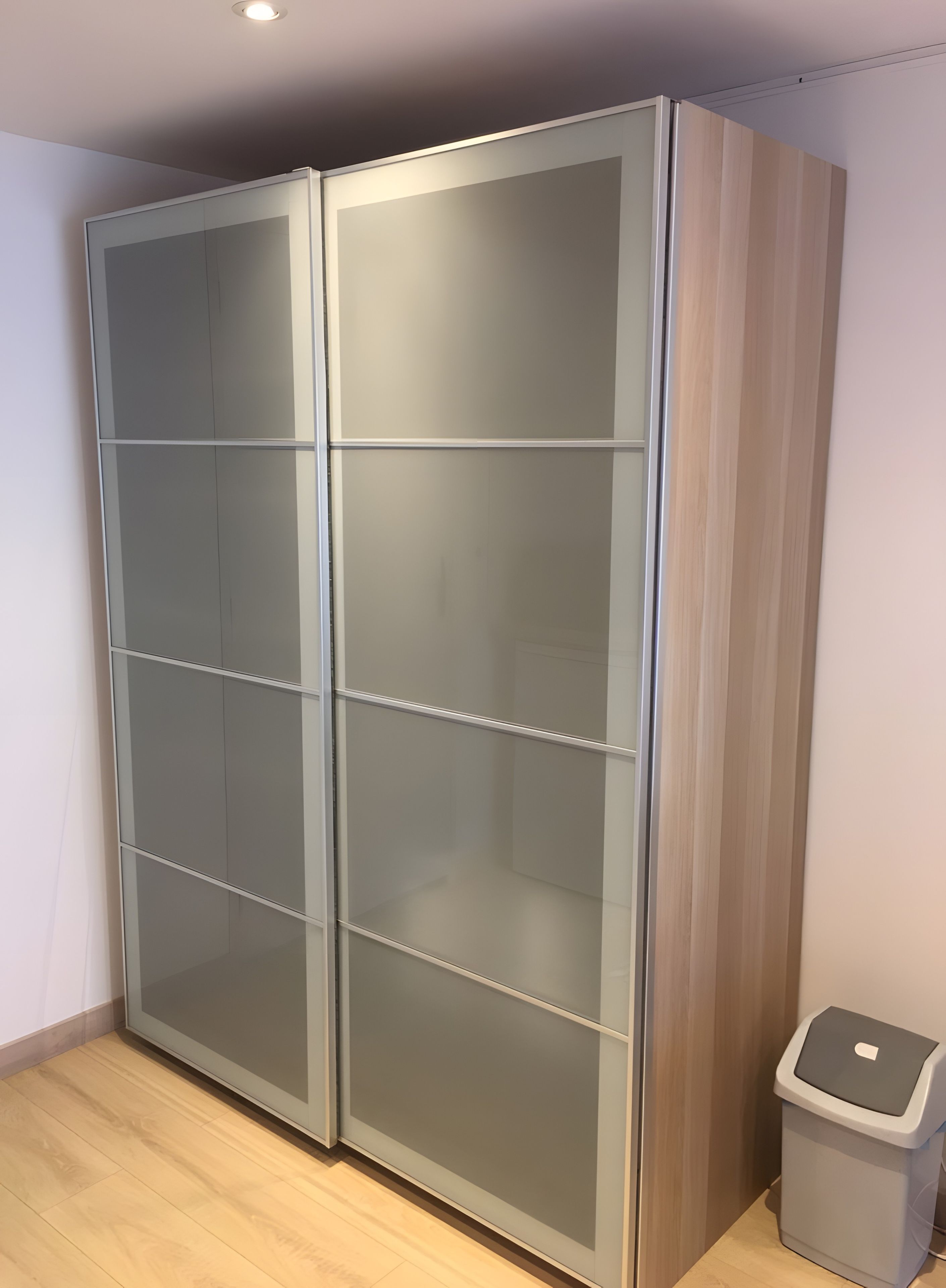 Une pièce dotée d’une grande armoire moderne à plusieurs portes et d’une poubelle.