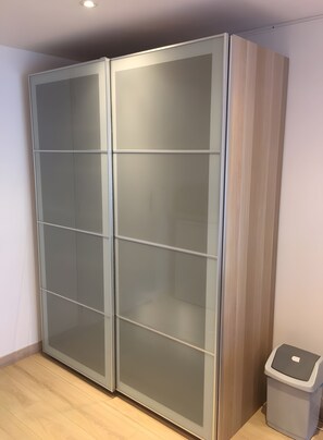 A room with a large, modern wardrobe with multiple doors and a trash bin.