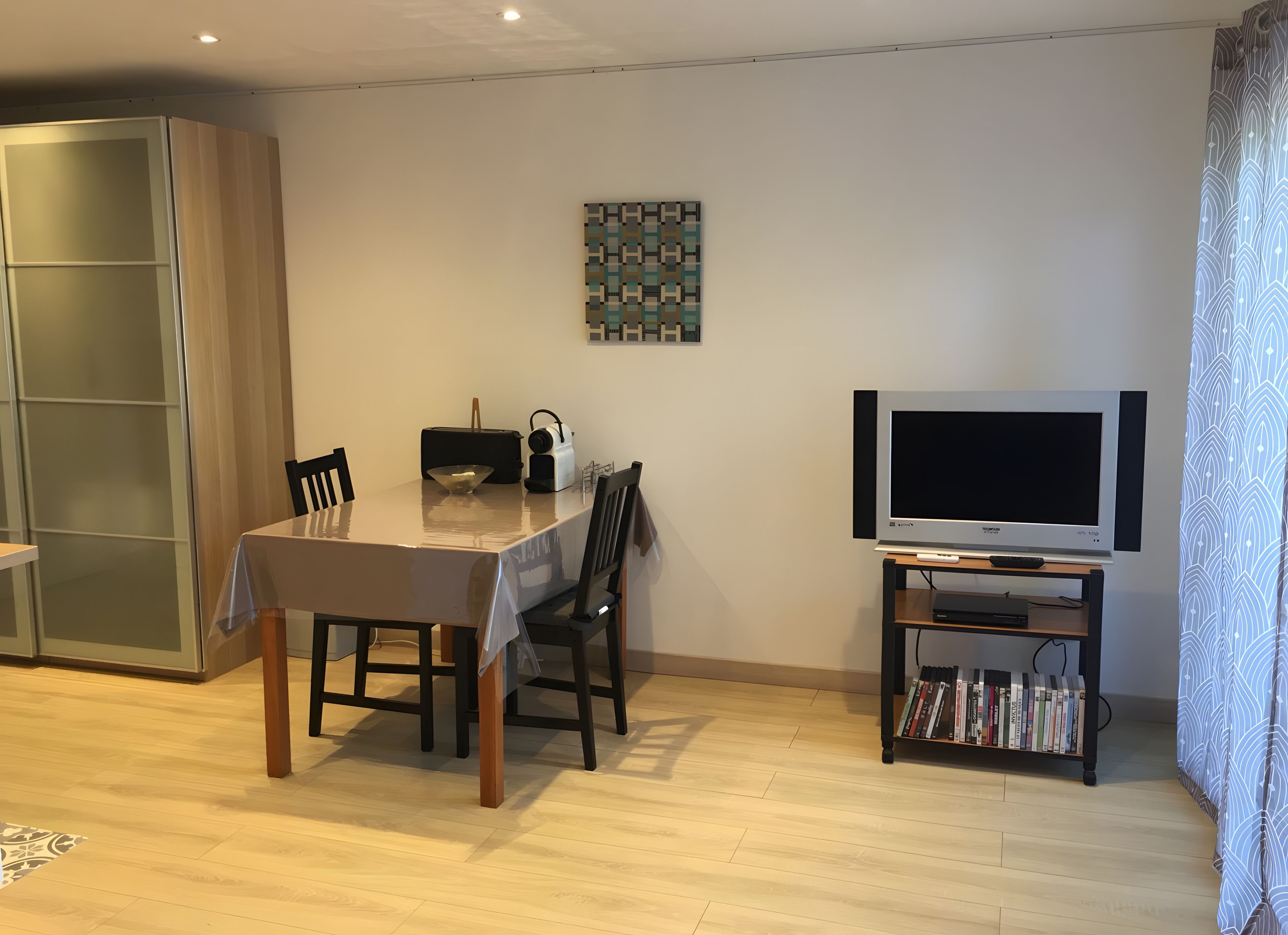 Un coin repas comprenant une table, des chaises, un téléviseur et une bibliothèque.