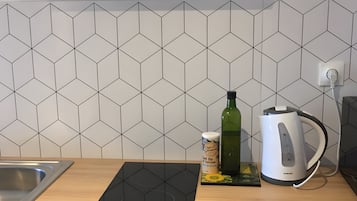A kitchen with a black induction cooktop, a kettle, and a bottle of olive oil on the counter.