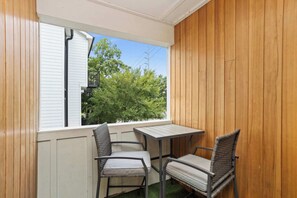 Ein Balkon mit Holzverkleidung, einem Fenster und zwei Stühlen mit einem kleinen Tisch.