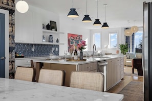 A modern kitchen with a central island, pendant lighting, and a dining area with wicker chairs. - Hot Tub Hang Grill Parking  Views of Downtown (Nashville)