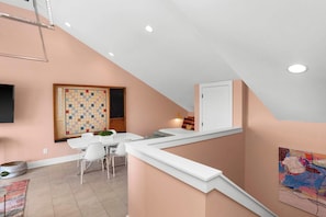 A modern kitchen with a white countertop, a large chessboard, and a dining area with chairs and a table. - 8 Beds | Minutes to Broadway, Gulch & 12 South (Nashville)