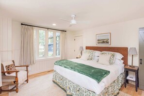 A bedroom with a large bed, a chair, a nightstand, a lamp, and a ceiling fan. - 7  Cottages at Buckhorn Hollow - Sleeps 28 (McEwen)