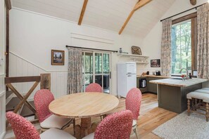 A cozy kitchen with a round wooden table and red patterned chairs, a white refrigerator, and a window with curtains. - 7  Cottages at Buckhorn Hollow - Sleeps 28 (McEwen)