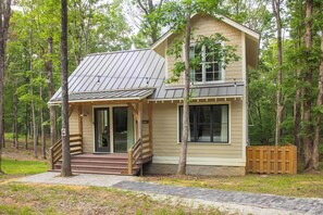 A two-story cabin with a porch, a staircase, and a wooden fence. - 7  Cottages at Buckhorn Hollow - Sleeps 28 (McEwen)