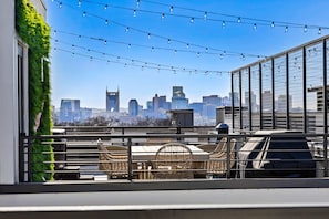 A rooftop terrace with a city skyline view, string lights, and outdoor furniture. - THE LUCY | Hot Tub | Views | Grill | Parking (Nashville)