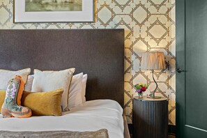 A neatly made bed with multiple pillows and a decorative boot. There is a lamp on a small table beside the bed. - THE LUCY | Hot Tub | Views | Grill | Parking (Nashville)