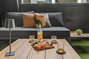 A cozy seating area with a sofa, a tray of snacks, a bottle of whiskey, and glasses of whiskey on a wooden table. - Songwriters' Retreat: 4BR, Rooftop Sauna & Bar (Nashville)