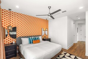 Ein Schlafzimmer mit Bett, Nachttischen, einem Deckenventilator und gemustertem Wandpapier.
