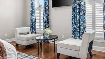 A living room with two armchairs, a coffee table, and a flat-screen TV mounted on the wall.
