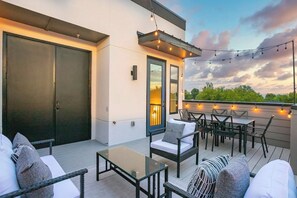 Eine Terrassensitzgruppe im Freien mit Sitzgelegenheiten, einem Glastisch und Lichterketten.
