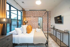 A modern hotel room with a large bed, a desk, and a TV. - 2 Mi to DT + King Beds & Garage (Nashville)